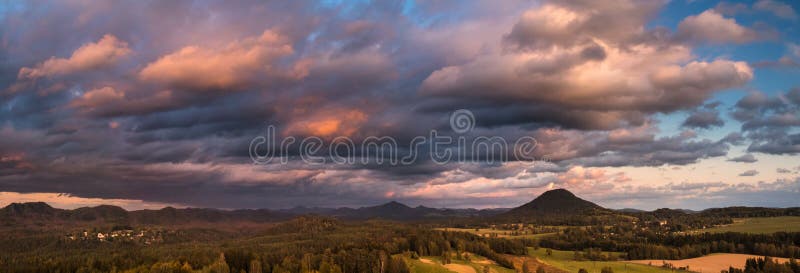 Paisaje otoñal al atardecer - montañas, bosques y nubes dramáticas iluminadas por el sol abrasador imagenes de archivo Paisaje otoñal al atardecer - montañas, bosques y nubes dramáticas iluminadas por el sol abrasador imagenes de archivo