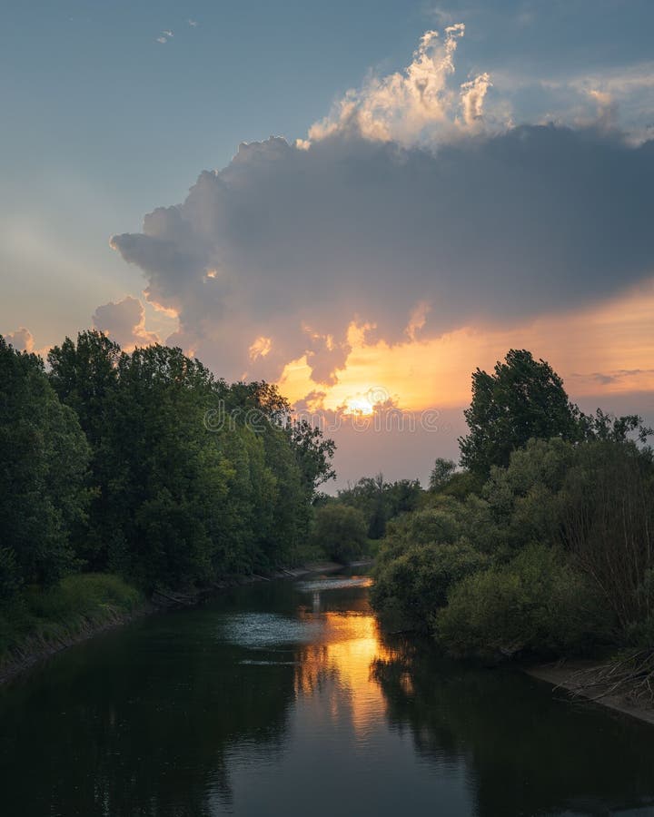 Paisaje sereno al atardecer con un cielo dramático y árboles verdes que reflejan el agua imágenes de archivo libres de regalías