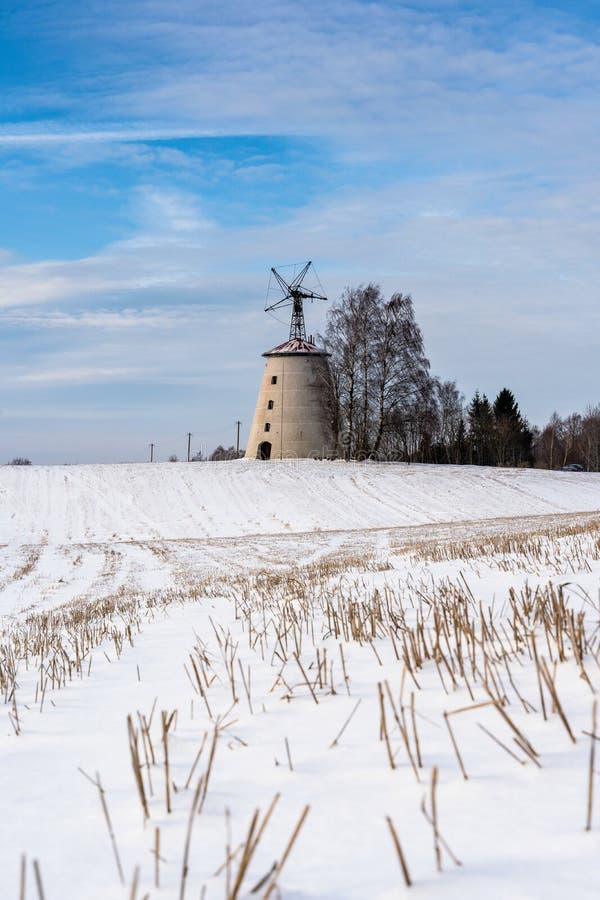 Paisaje vacío del campo en Sunny Winter Day con la nieve que cubre la tierra con el molino de viento abandonado grande en fondo fotos de archivo Paisaje vacío del campo en Sunny Winter Day con la nieve que cubre la tierra con el molino de viento abandonado grande en fondo fotos de archivo
