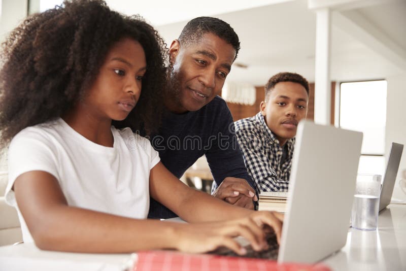 Paizinho afro-americano envelhecido m?dio que ajuda suas crian?as adolescentes com trabalhos de casa, baixo ?ngulo, fim acima fotos de stock Paizinho afro-americano envelhecido m?dio que ajuda suas crian?as adolescentes com trabalhos de casa, baixo ?ngulo, fim acima fotos de stock