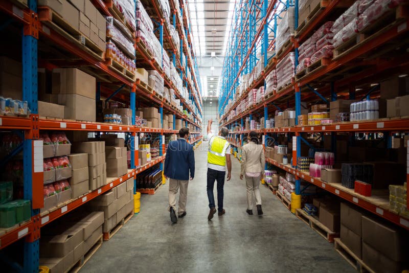 Pakhuisteam die terwijl het lopen in pakhuis bespreken stock afbeeldingen Pakhuisteam die terwijl het lopen in pakhuis bespreken stock afbeeldingen