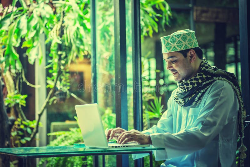 Pakistanska muslim Man arbete på bärbara datorn i kafé royaltyfri fotografi Pakistanska muslim Man arbete på bärbara datorn i kafé royaltyfri fotografi