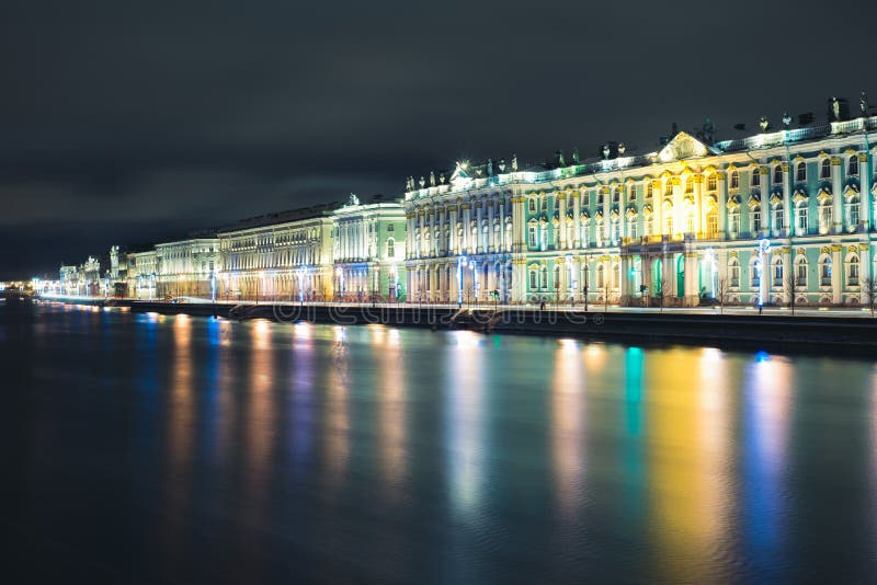 View of the Winter Palace from the Palace bridge on Neva river during the white nights in St. Petersburg. In the river reflected the lights of street lighting and lighting of the building. View of the Winter Palace from the Palace bridge on Neva river during the white nights in St. Petersburg. In the river reflected the lights of street lighting and lighting of the building.