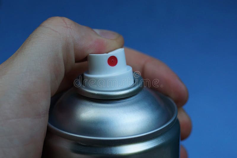 Palce naciskają biały plastikowy dozownik na szarej metalowej puszce