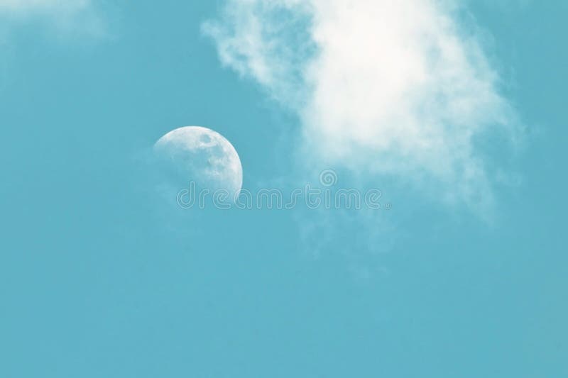 Pale morning moon in a blue sky with clouds