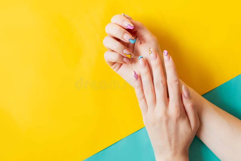 Youth summer funny cheerful colorful acrylic manicure. Gel polish nails with a fun stylish design. Colored background yellow. Place for text copy space. beauty salon trendy. Youth summer funny cheerful colorful acrylic manicure. Gel polish nails with a fun stylish design. Colored background yellow. Place for text copy space. beauty salon trendy