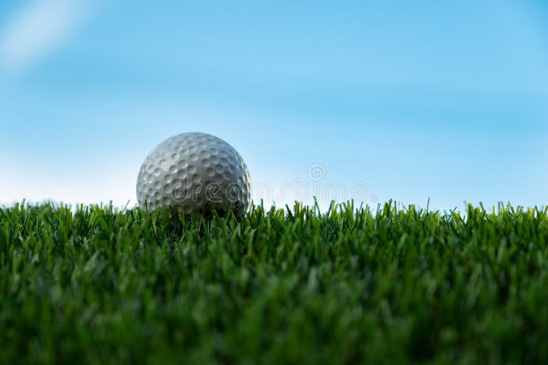 Palla da golf su erba nel fondo del cielo blu fotografia stock libera da diritti Palla da golf su erba nel fondo del cielo blu fotografia stock libera da diritti