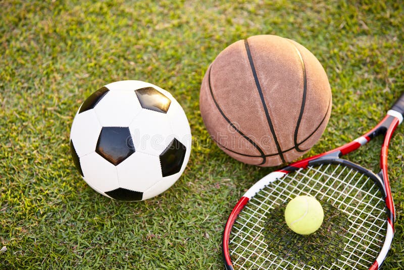 Pallacanestro di calcio e pallina da tennis e racchetta su erba fotografia stock libera da diritti Pallacanestro di calcio e pallina da tennis e racchetta su erba fotografia stock libera da diritti
