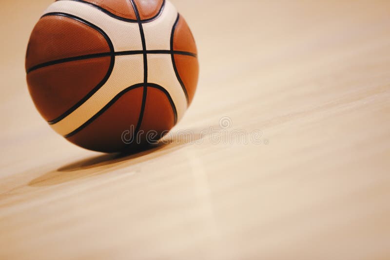 Pallacanestro sulla fine di legno del pavimento della corte su con l'arena vaga nel fondo fotografie stock libere da diritti Pallacanestro sulla fine di legno del pavimento della corte su con l'arena vaga nel fondo fotografie stock libere da diritti