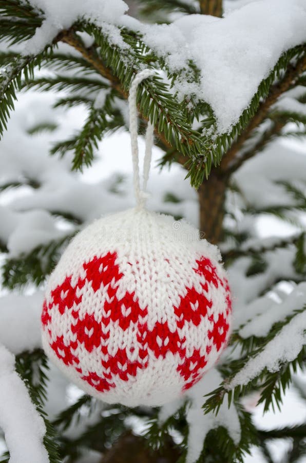 Palle tricottate per decorazione dell'albero di Natale e del nuovo anno che appende sul ramo attillato coperto di neve immagini stock libere da diritti Palle tricottate per decorazione dell'albero di Natale e del nuovo anno che appende sul ramo attillato coperto di neve immagini stock libere da diritti