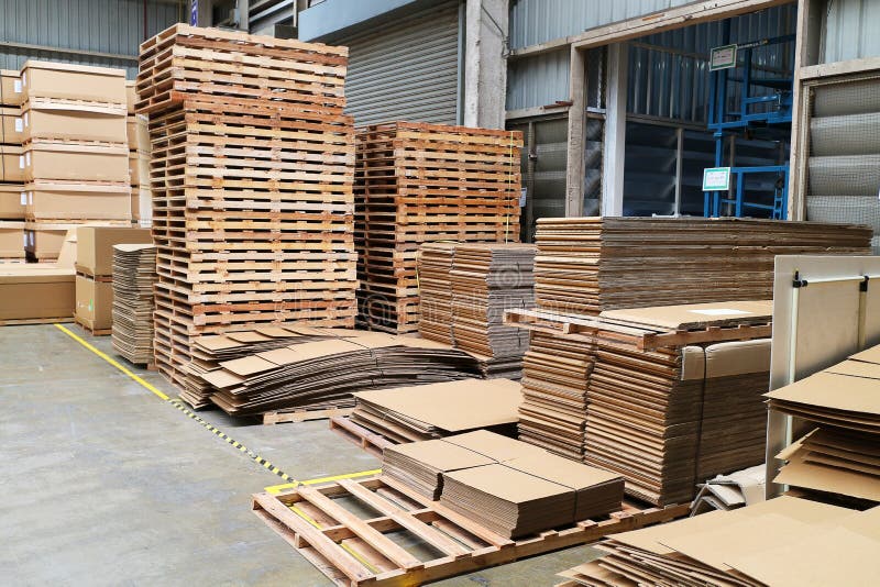 Pallet di legno e scatole di carta nel magazzino della fabbrica fotografie stock libere da diritti Pallet di legno e scatole di carta nel magazzino della fabbrica fotografie stock libere da diritti