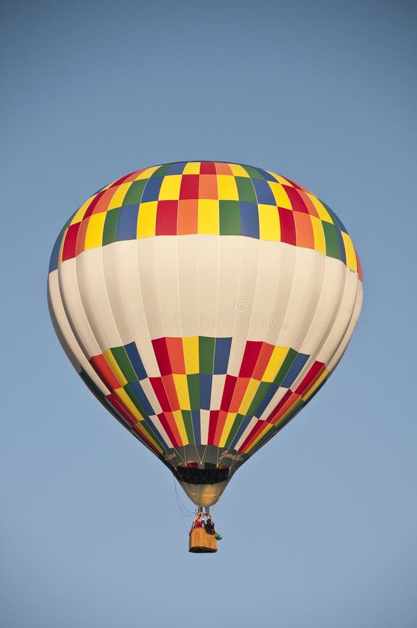 Pallone d'aria calda colorata che vola contro il cielo mattutino blu fotografia stock Pallone d'aria calda colorata che vola contro il cielo mattutino blu fotografia stock
