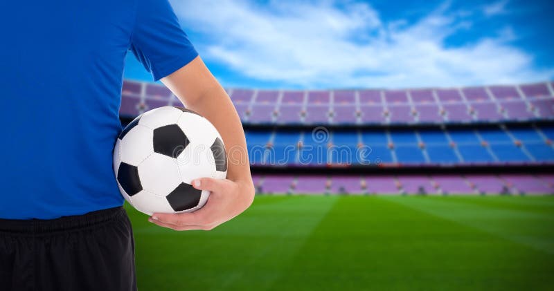 Pallone da calcio della tenuta del giocatore di football americano sul campo di grande stadio immagine stock Pallone da calcio della tenuta del giocatore di football americano sul campo di grande stadio immagine stock