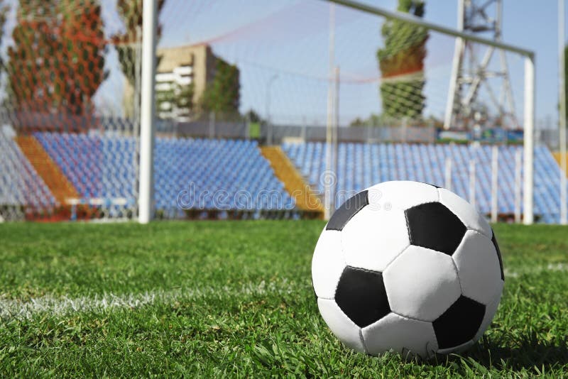 Pallone da calcio sull'erba verde del campo di football americano contro rete immagine stock libera da diritti Pallone da calcio sull'erba verde del campo di football americano contro rete immagine stock libera da diritti