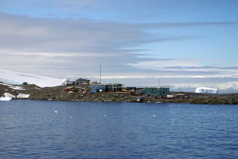 Palmer Station in Antarctica, in a peninsula, with an iceberg floating by in the background. Palmer Station in Antarctica, in a peninsula, with an iceberg floating by in the background