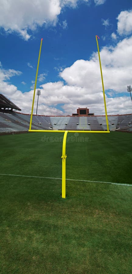 This is a goal post on a american football field in front of a score board. This is a goal post on a american football field in front of a score board