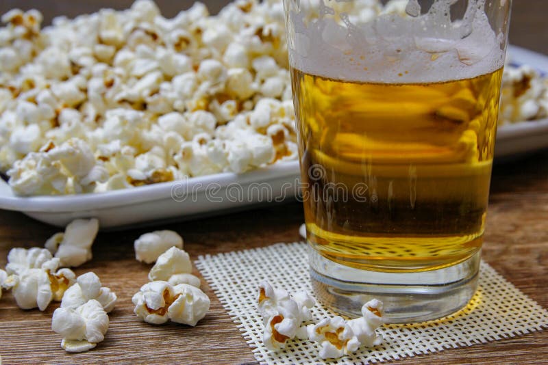Palomitas y cerveza en la tabla de madera foto de archivo Palomitas y cerveza en la tabla de madera foto de archivo