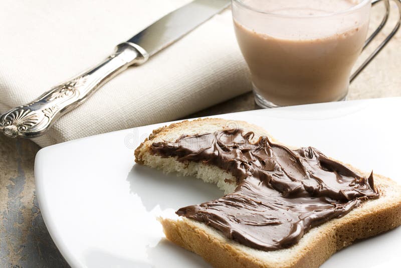 Pan blanco mordido con Nutella y leche fotografía de archivo Pan blanco mordido con Nutella y leche fotografía de archivo