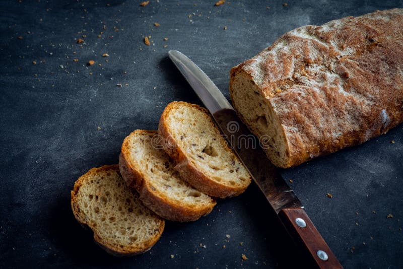 Pan de pan cortado con cuchillo sobre fondo oscuro fotos de archivo