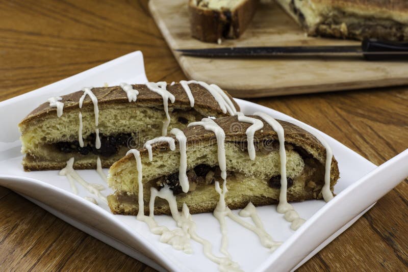 Nicely plated iced rain nut bread with loaf and knife in backgound on wood cutting board. Nicely plated iced rain nut bread with loaf and knife in backgound on wood cutting board