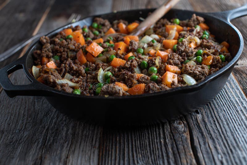 Pan Fried Ground Beef with Peas and Carrots in a Cast Iron Pan Stock