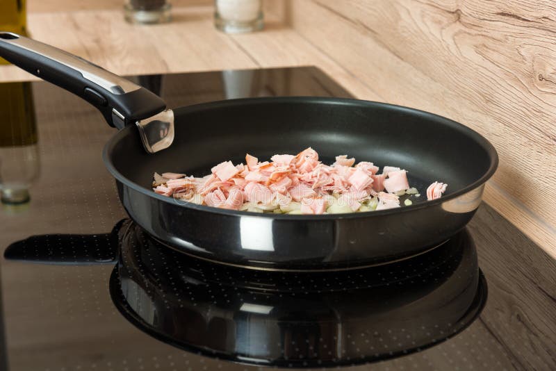 Pan with Ham and Onion Pieces an Modern Ceramic Cooking Surface Stock
