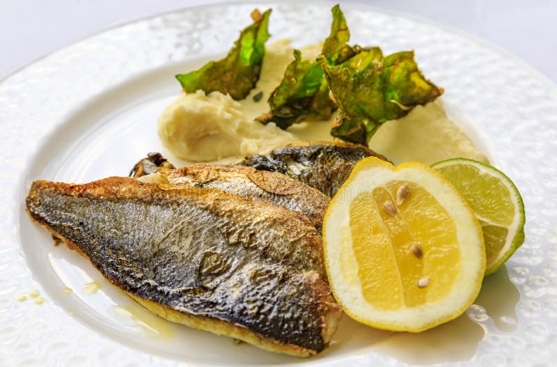 Pan seared branzino or sea bass with mashed potatoes and deep fried kale chips at an al fresco restaurant in Montenegro royalty free stock image Pan seared branzino or sea bass with mashed potatoes and deep fried kale chips at an al fresco restaurant in Montenegro royalty free stock image