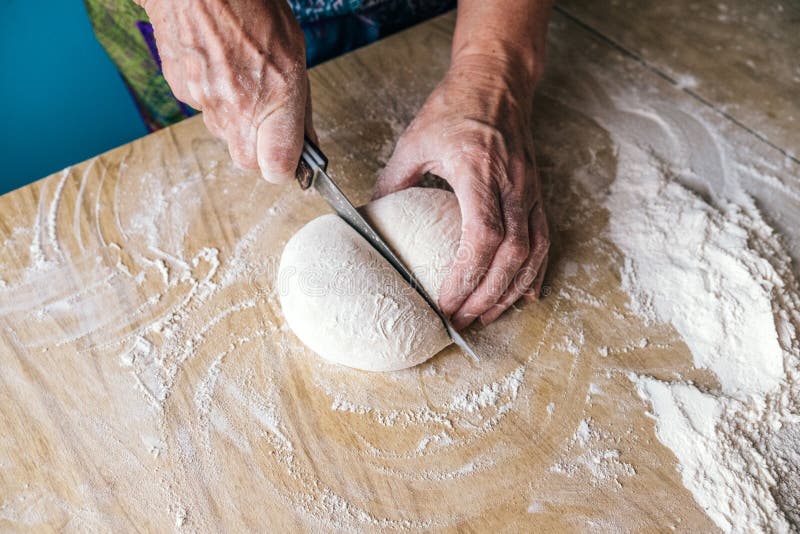 Panadero de una más vieja mujer que corta la pasta en la cocina casera imágenes de archivo libres de regalías Panadero de una más vieja mujer que corta la pasta en la cocina casera imágenes de archivo libres de regalías