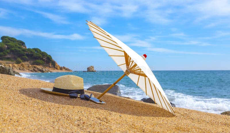 Panama-Hut und -Strandschirm auf dem sandigen Strand nahe dem Meer Sommerferien und Ferienkonzept für Tourismus