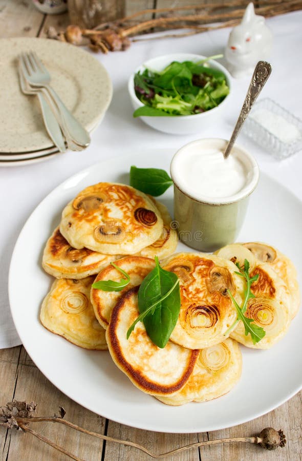 Pancake con i funghi e le cipolle, serviti con panna acida e un'insalata verde immagine stock Pancake con i funghi e le cipolle, serviti con panna acida e un'insalata verde immagine stock