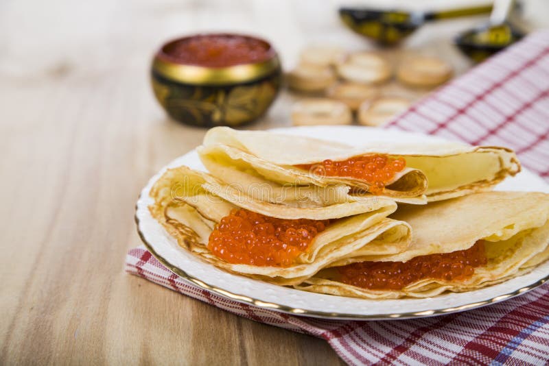 Pancake deliziosi con il caviale rosso su una tavola immagini stock libere da diritti Pancake deliziosi con il caviale rosso su una tavola immagini stock libere da diritti