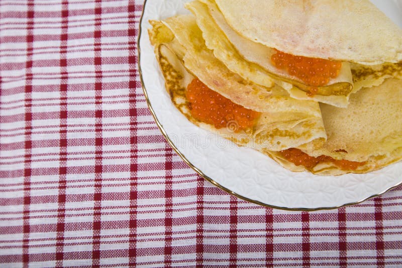 Pancake deliziosi con il caviale rosso su una tavola fotografia stock libera da diritti Pancake deliziosi con il caviale rosso su una tavola fotografia stock libera da diritti