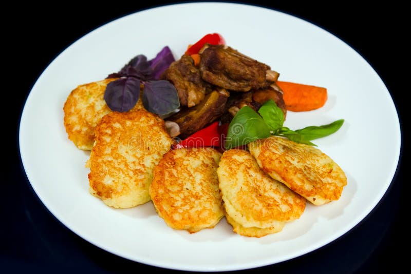 Pancake di patata fritti, costole di carne di maiale arrostite col barbecue, serviti con basilico, le carote arrostite e la papri immagini stock Pancake di patata fritti, costole di carne di maiale arrostite col barbecue, serviti con basilico, le carote arrostite e la papri immagini stock