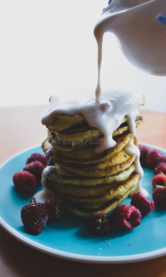 Pancake with flowing yogurt on a blue plate with raspberries