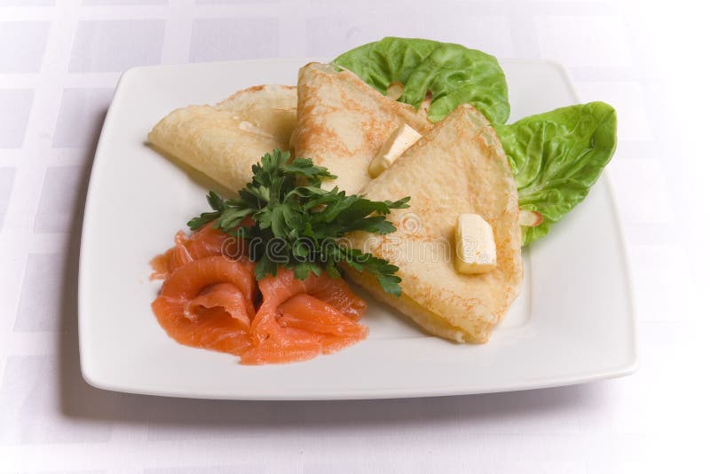 Pancakes with salty salmon on white plate