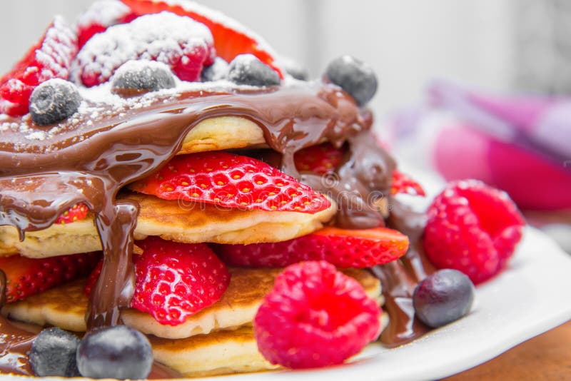 Dish with pancakes and strawberry,raspberry and blueberry and chocolate