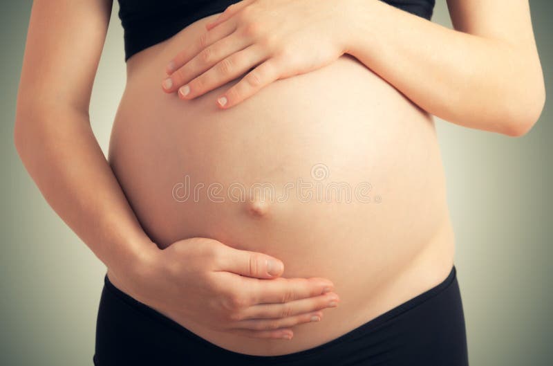 Belly and hands of pregnant woman in dark colors. Belly and hands of pregnant woman in dark colors