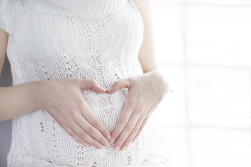 Pancia della donna incinta, forma del cuore di gravidanza, segno di amore fotografia stock libera da diritti
