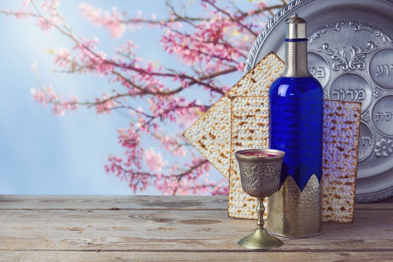 Passover matzo and wine on wooden vintage table over blossom tree background. Seder plate with hebrew text says bone and lettuce. Passover matzo and wine on wooden vintage table over blossom tree background. Seder plate with hebrew text says bone and lettuce.