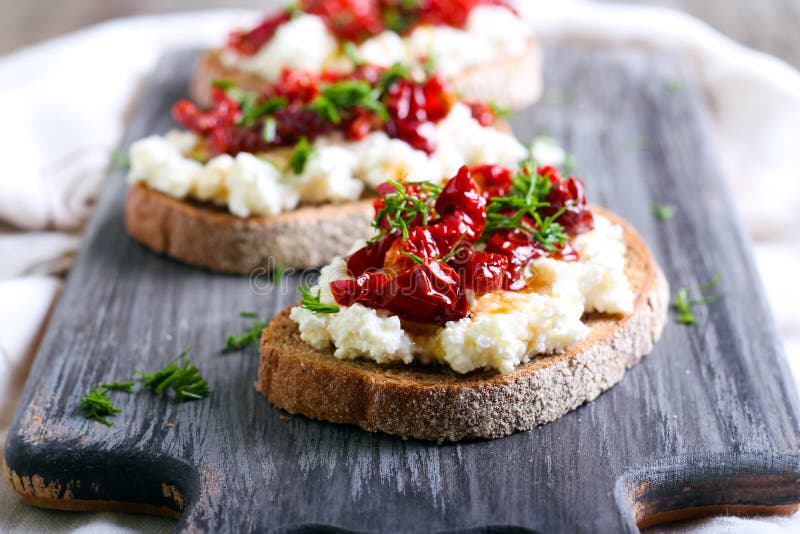 Pane fatias com queijo da ricota e, tomates secados sol fotografia de stock royalty free Pane fatias com queijo da ricota e, tomates secados sol fotografia de stock royalty free