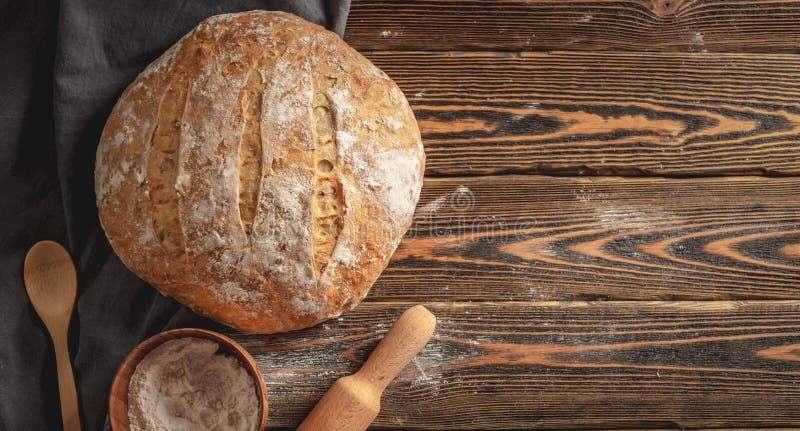 Pane naturale fatto in casa con una crosta dorata su un tovagliolo su un vecchio sfondo di legno. prodotti di panetteria. stile ru fotografia stock