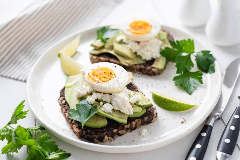 Pane tostato saporito sano con l'avocado, il formaggio bianco e l'uovo sodo fotografia stock libera da diritti