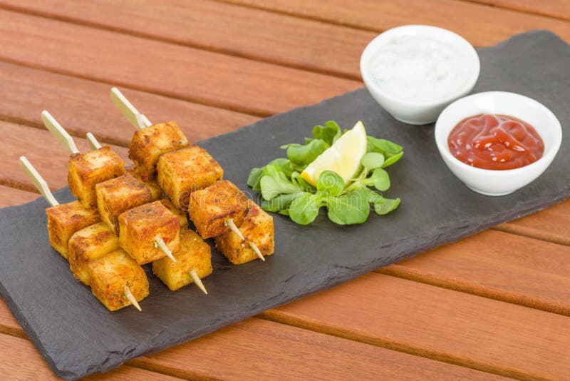 Indio queso brochetas servimos sobre el pizarra limón, salsa pepino cebolla yogur raito.