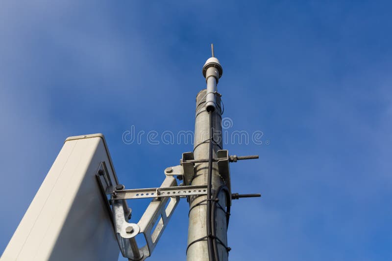 Panel antenna of GSM DCS UMTS LTE bands and GPS antenna are as part of communication equipment of basic station are installed on the tubular mast and sky and city are as background. Panel antenna of GSM DCS UMTS LTE bands and GPS antenna are as part of communication equipment of basic station are installed on the tubular mast and sky and city are as background.