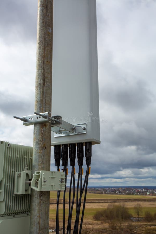 Panel antenna of GSM DCS UMTS LTE bands and outdoor remote radio unit are as part of communication equipment of basic station are installed on the tubular mast on the roof. Panel antenna of GSM DCS UMTS LTE bands and outdoor remote radio unit are as part of communication equipment of basic station are installed on the tubular mast on the roof.