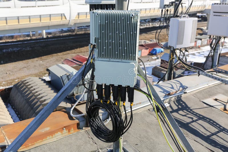 Panel antenna of GSM DCS UMTS LTE bands and outdoor remote radio unit are as part of communication equipment of basic station are installed on the tubular mast on the roof. Panel antenna of GSM DCS UMTS LTE bands and outdoor remote radio unit are as part of communication equipment of basic station are installed on the tubular mast on the roof.