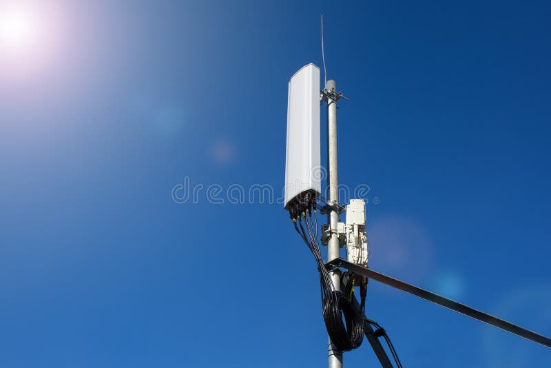 Panel antenna of GSM DCS UMTS LTE bands and radio unit are as part of communication equipment of basic station are installed on the roof and blue sky as background. Panel antenna of GSM DCS UMTS LTE bands and radio unit are as part of communication equipment of basic station are installed on the roof and blue sky as background.