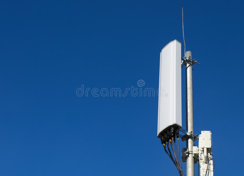 Panel antenna of GSM DCS UMTS LTE bands and radio unit are as part of communication equipment of basic station are installed on the roof and blue sky as background and space for text. Panel antenna of GSM DCS UMTS LTE bands and radio unit are as part of communication equipment of basic station are installed on the roof and blue sky as background and space for text.