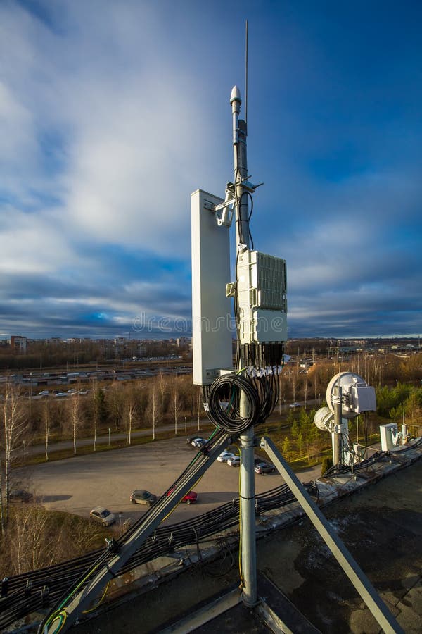 Panel antenna of GSM DCS UMTS LTE bands and radio unit are as part of communication equipment of basic station are installed on the roof and sky and city are as background. Panel antenna of GSM DCS UMTS LTE bands and radio unit are as part of communication equipment of basic station are installed on the roof and sky and city are as background