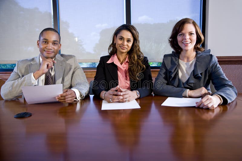 Multiethnic professional workers sitting in a row looking at camera. Multiethnic professional workers sitting in a row looking at camera